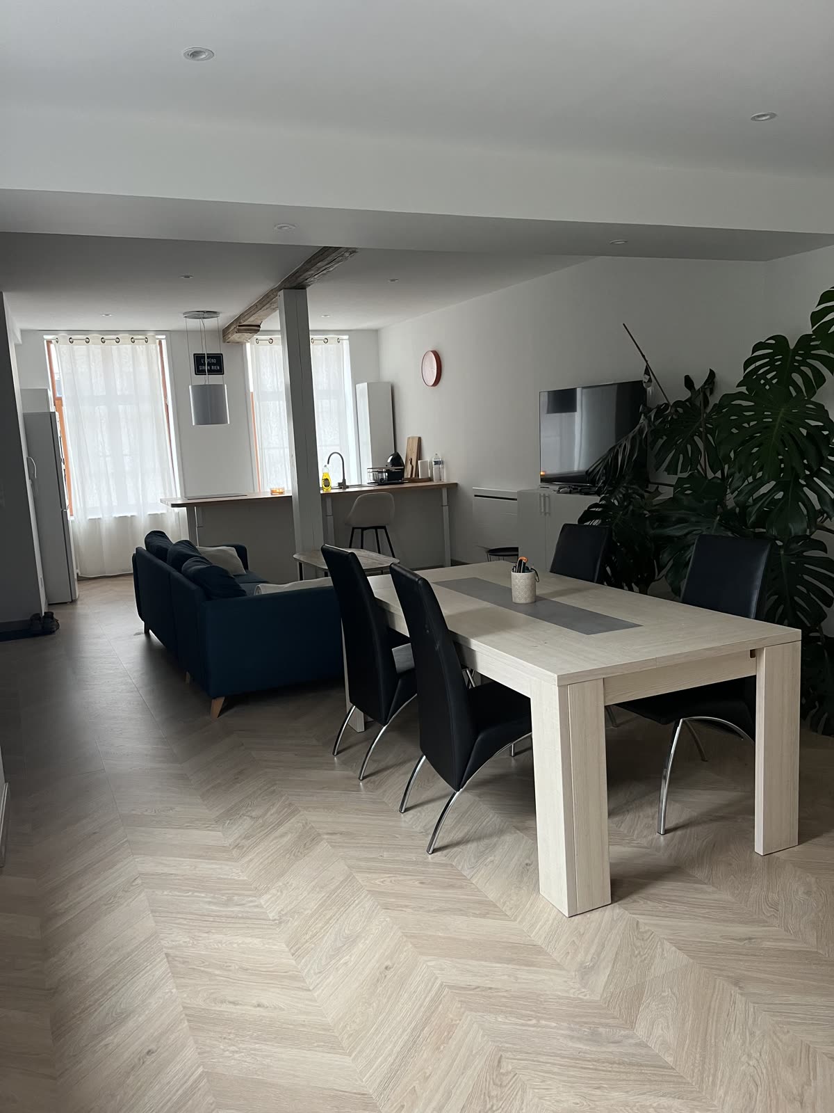 Pièce de vie rénovée par VN Design : parquet à chevrons, cuisine ouverte et poutre apparente